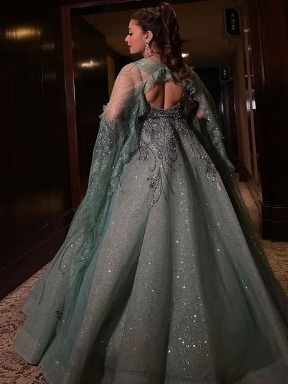 The back view of the sparkling grey-green gown, highlighting the sheer cape and the dress's voluminous train.