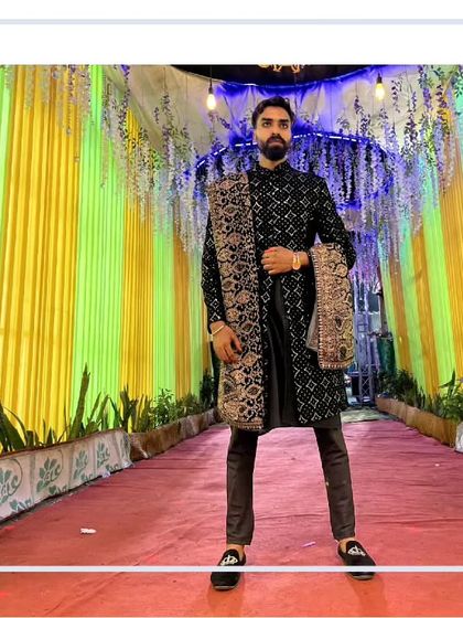 Our client looking sharp against a festive backdrop. This black sherwani with a detailed dupatta is a classic and powerful statement for any wedding event.