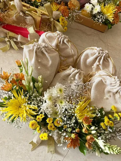Bright and colorful floral platters make for stunning wedding gifts. This arrangement features yellow and orange chrysanthemums, tuberoses, and jute potlis.