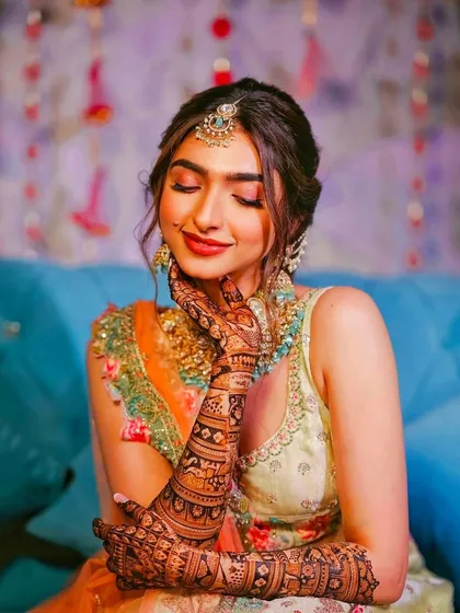 A happy bride beautifully showcasing her full-arm bridal mehandi. Seeing my clients smile is the best part of my work, and this design captures the joy of the occasion.