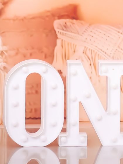 I have a variety of props to make your baby's first birthday shoot special, including these light-up marquee letters that spell 'ONE', adding a touch of sparkle to the celebration.