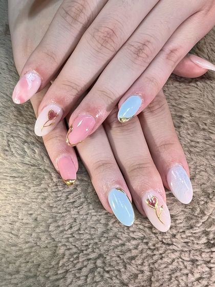 A romantic and artistic set. Soft pink and baby blue nails are accented with delicate gold chrome details and tiny, hand-painted tulip illustrations.
