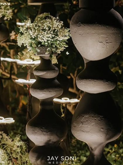 A close-up of the whimsical flower-shaped lights at night, showing how they create a beautiful, soft glow amidst the dark, sculptural vases and greenery.
