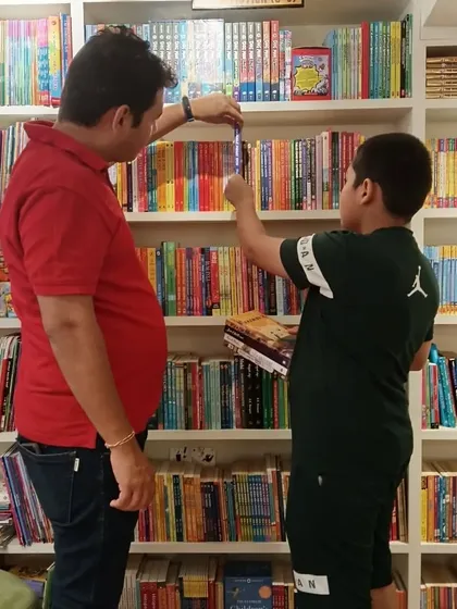 A father and son picking out a book together from our colorful shelves. We love seeing families bond over the shared experience of choosing the next story to read.