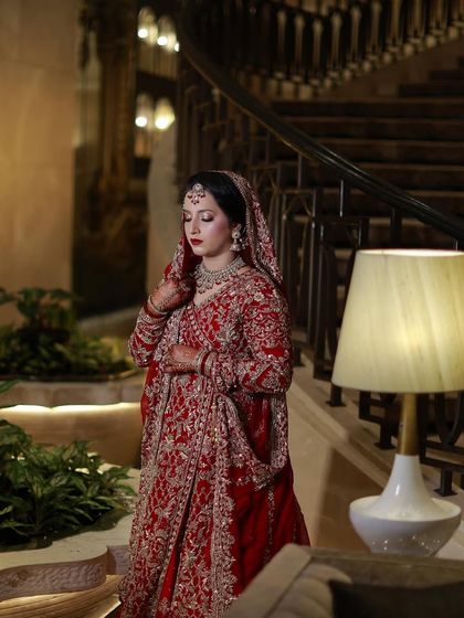 A full portrait of the bride on a grand staircase. Her makeup and outfit create a look of timeless elegance.