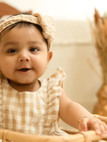 A heart-melting smile from a baby girl in a gingham dress. We focus on close-ups to capture these precious expressions.