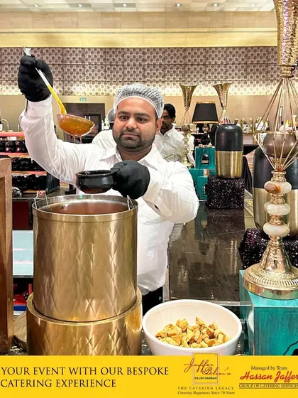 Our professional staff ensures every guest feels attended to. Here, one of our chefs serves a warm, comforting soup from a traditional golden urn, representing the bespoke and luxurious catering experience we provide at every event.