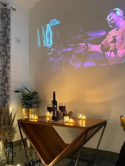 A table set with wine and candles while a Coke Studio performance plays on the screen, creating a sophisticated and cool vibe.