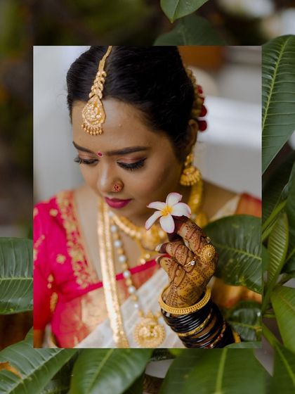 A portrait of a bride on her muhurtham day, holding a small white flower and looking serene.