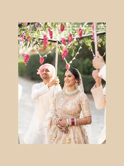 A close up of the bride during her entrance. Her hair is neatly styled with a center part to accommodate her maang tikka.