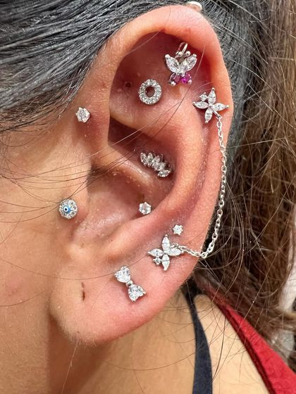 A closer look at the details in this beautiful silver stack. The combination of a chained stud, butterfly, bow, and floral pieces creates a feminine and intricate style.