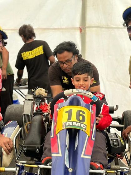 The team helping a very young driver get comfortable in his kart.