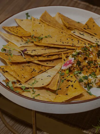 A bowl of creamy hummus topped with fried onions and served with crispy tortilla chips. We elevate classic international dips with our unique finishing touches.