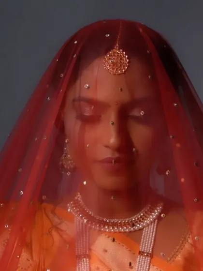 A dramatic shot of the bride under her red veil, creating a sense of mystery and anticipation.