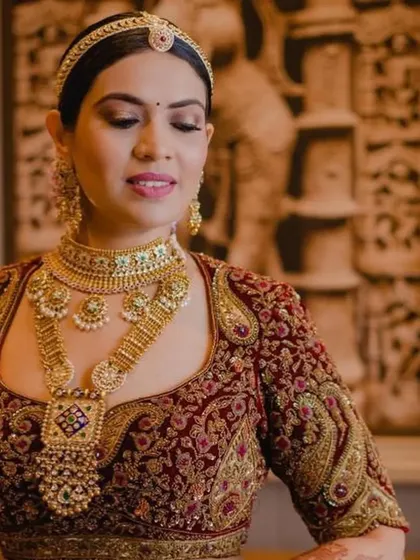 A beautiful shot of a bride with a classic floral bun, showcasing her stunning jewellery and makeup. The updo provides a perfect canvas for the entire look.