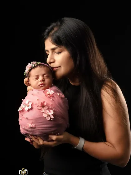 A mother's gentle embrace. This simple, elegant portrait against a black background puts all the focus on the tender connection between a mother and her newborn baby.