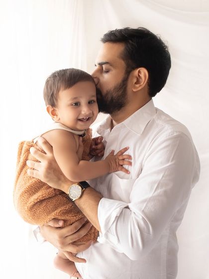 A father's loving kiss for his smiling baby. This bright and simple portrait is a beautiful example of capturing a tender dad and child moment.