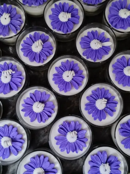 An overhead view of a large order of purple flower jar candles.
