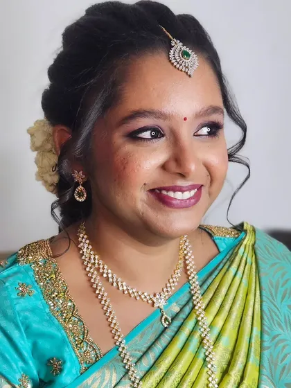 A smiling shot of Jebha during her engagement, looking happy and radiant in her blue and green saree.