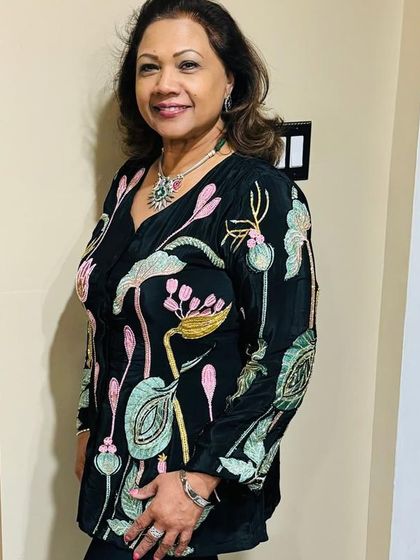 A client looking elegant in a black tunic with beautiful floral embroidery. She has paired it with a stunning silver-tone necklace set with a green stone, adding a pop of color.