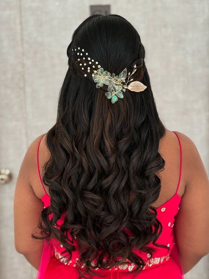 A romantic half-up, half-down hairstyle with soft waves. The look is completed with a delicate, nature-inspired hair accessory.