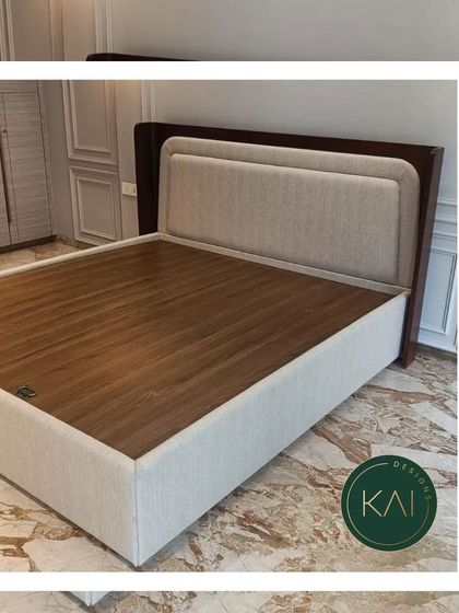 A beautifully crafted bed with a dual-panel upholstered headboard framed in dark wood, set on a sleek, upholstered base. This piece is designed to complement a room with luxurious marble flooring and classic wall molding.