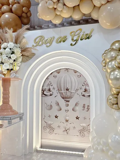 The 'Boy or Girl' sign in elegant gold script above the arched backdrop, adding an element of suspense and fun for a gender reveal party.