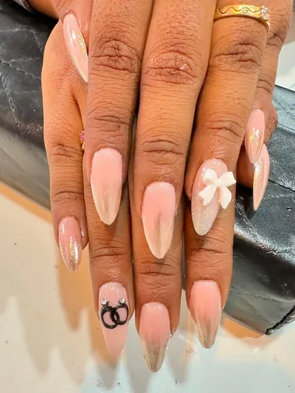 This engagement nail set features a pearlescent chrome base with a 3D bow and a custom accent nail showing two intertwined rings.