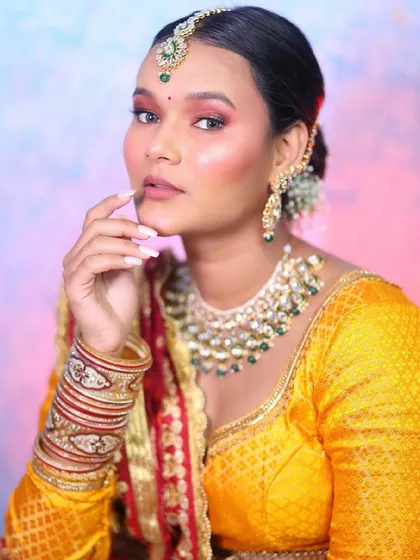 A stunning look featuring a yellow and red lehenga. The makeup has warm, sunset tones on the eyes to match the outfit, creating a vibrant and cohesive look.