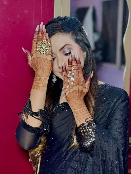 A playful pose highlighting the detailed henna and the stunning party makeup.