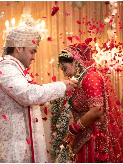The Varmala ceremony, showered in rose petals. This iconic moment is captured to show the joy and significance of the couple's union.