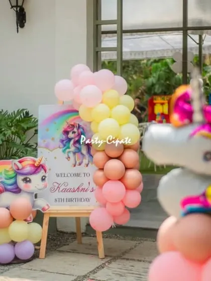 The welcome easel for the unicorn party, decorated with a pastel balloon garland and a cute unicorn cutout.
