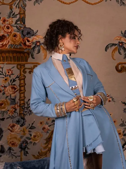 This profile shot shows the interplay between the makeup, the structured outfit, and the soft, curly hair.