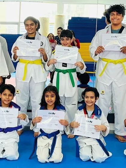 The pride of achievement. Here, a group of our students, both children and adults, proudly display their certificates after a successful Taekwondo belt promotion event, marking a significant step forward in their martial arts journey.