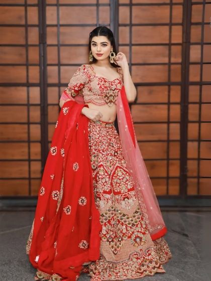 A beautiful bride-to-be modeling a classic red lehenga. This outfit is perfect for making a grand entrance and creating unforgettable wedding memories.
