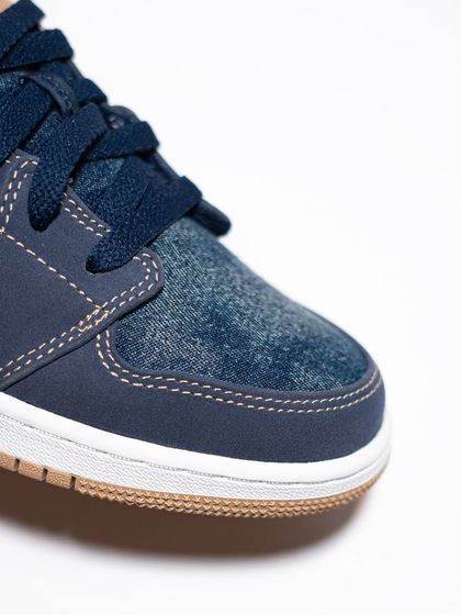 A detailed look at the toe box of the Jordan 1 Low 'Denim', showing the unique denim material and nubuck overlays.