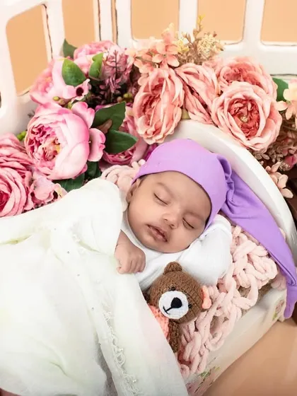 Another angle of the vintage-themed newborn setup. This shot shows the baby peacefully sleeping with a tiny teddy bear, adding to the nostalgic feel.