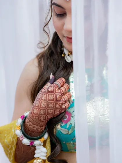 An artistic shot of the bride and her deep henna stain, partially hidden by a veil.