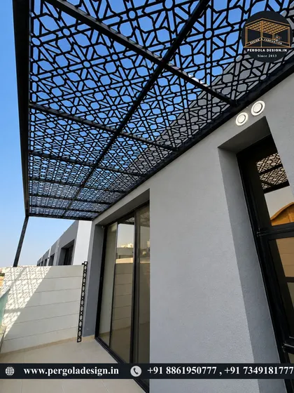 This cantilevered roof structure extends over a balcony, featuring a single, intricate laser-cut pattern across the entire surface. The design provides shade and privacy for the glass doors below while adding a modern, decorative element to the building's exterior.