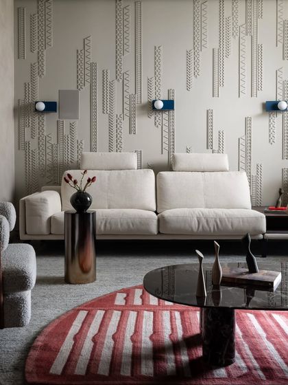 In the living area of Scarlet Horizon, we adorned the walls with custom paneling inspired by jewelry design. This intricate, vertical composition adds visual depth and an ornamental quality, balanced by the soft textures of the cream sofa and the bold, striped rug.