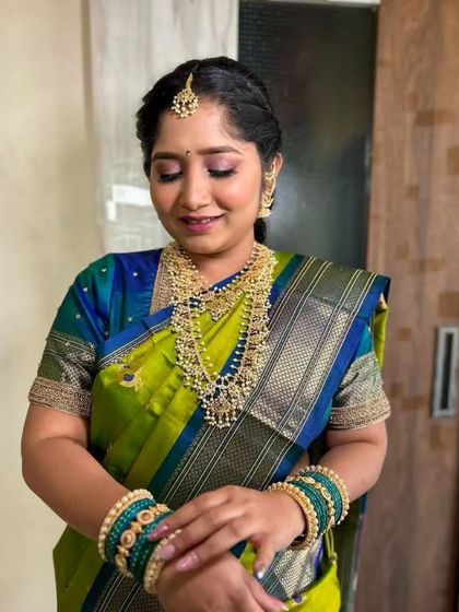 A beautiful Maharashtrian engagement look. The bride's green and blue saree is paired with traditional pearl jewelry and a soft, glowing makeup finish.