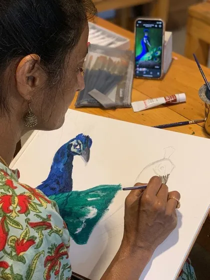 An artist paints a peacock, a subject rich in color and detail. The natural light from the windows provides a perfect setting for working with vibrant acrylics and watercolors.
