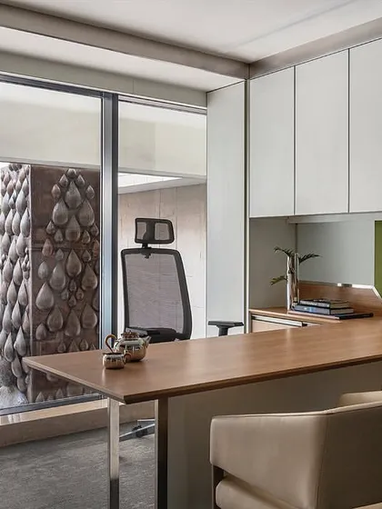 This cabin in 'The Layered Office' is designed for simplicity and functionality, with a large desk and integrated storage. A full-height window provides a direct view into the central courtyard, connecting the workspace with the building's core architectural feature.