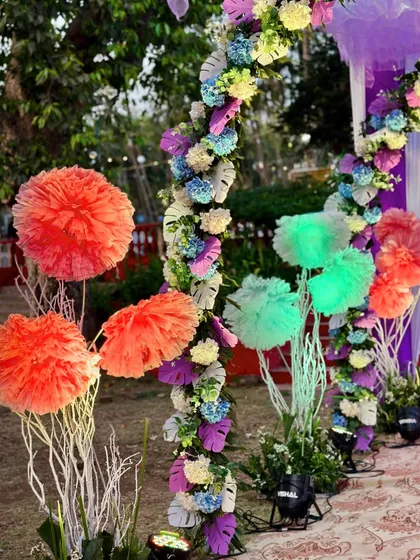 Close-up of the colorful pom-poms and floral arrangements lining the entrance path of a festive Haldi event.