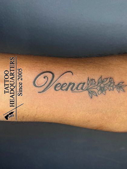The name "Veena" in a beautiful script, with a delicate floral design extending from the end of the name.