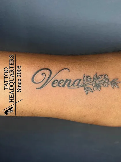 The name "Veena" in a beautiful script, with a delicate floral design extending from the end of the name.