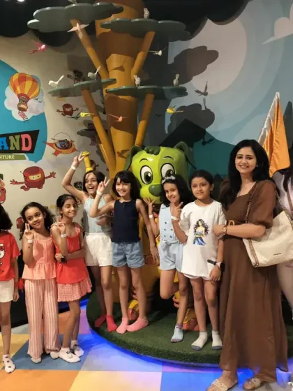 A group of girls and their moms pose near our main logo, enjoying a fun day out together.