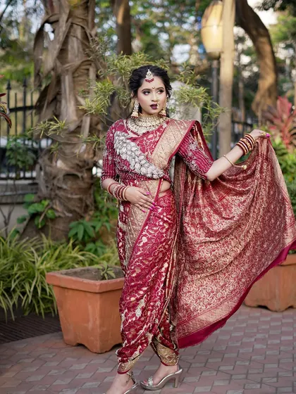 A full-length view of a bride in a stunning maroon `Navari` saree. I ensure the draping is perfect to create an elegant and powerful silhouette for the modern Maharashtrian bride.