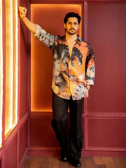 A full-length view of Sidharth's look. We paired the vibrant shirt with relaxed black trousers and boots to keep the focus on the statement piece while maintaining a polished feel.