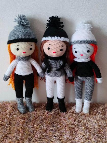 These dolls are ready for winter. They are wearing warm pants, sweaters, and hats with pom-poms.